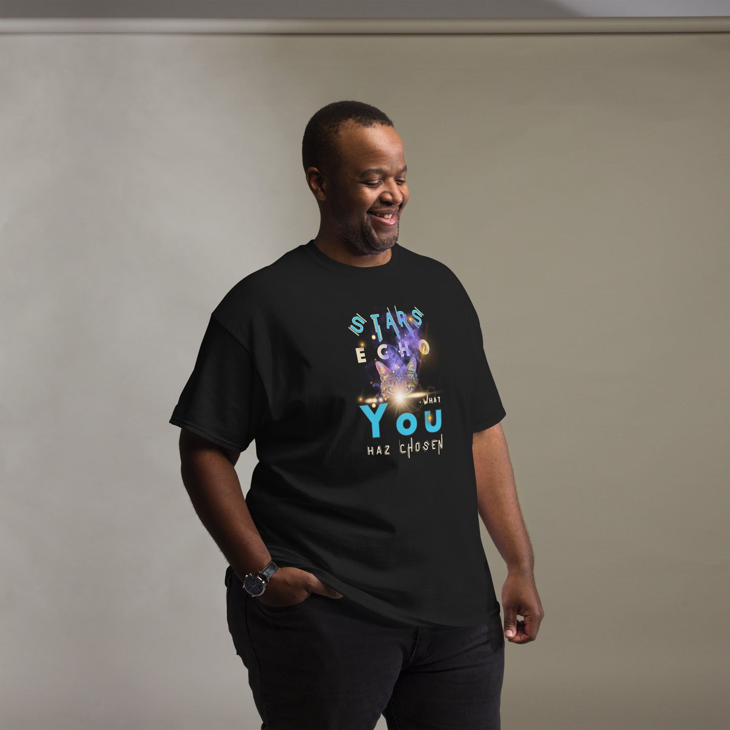 Man wearing a black t-shirt with colorful text and graphics on a plain background