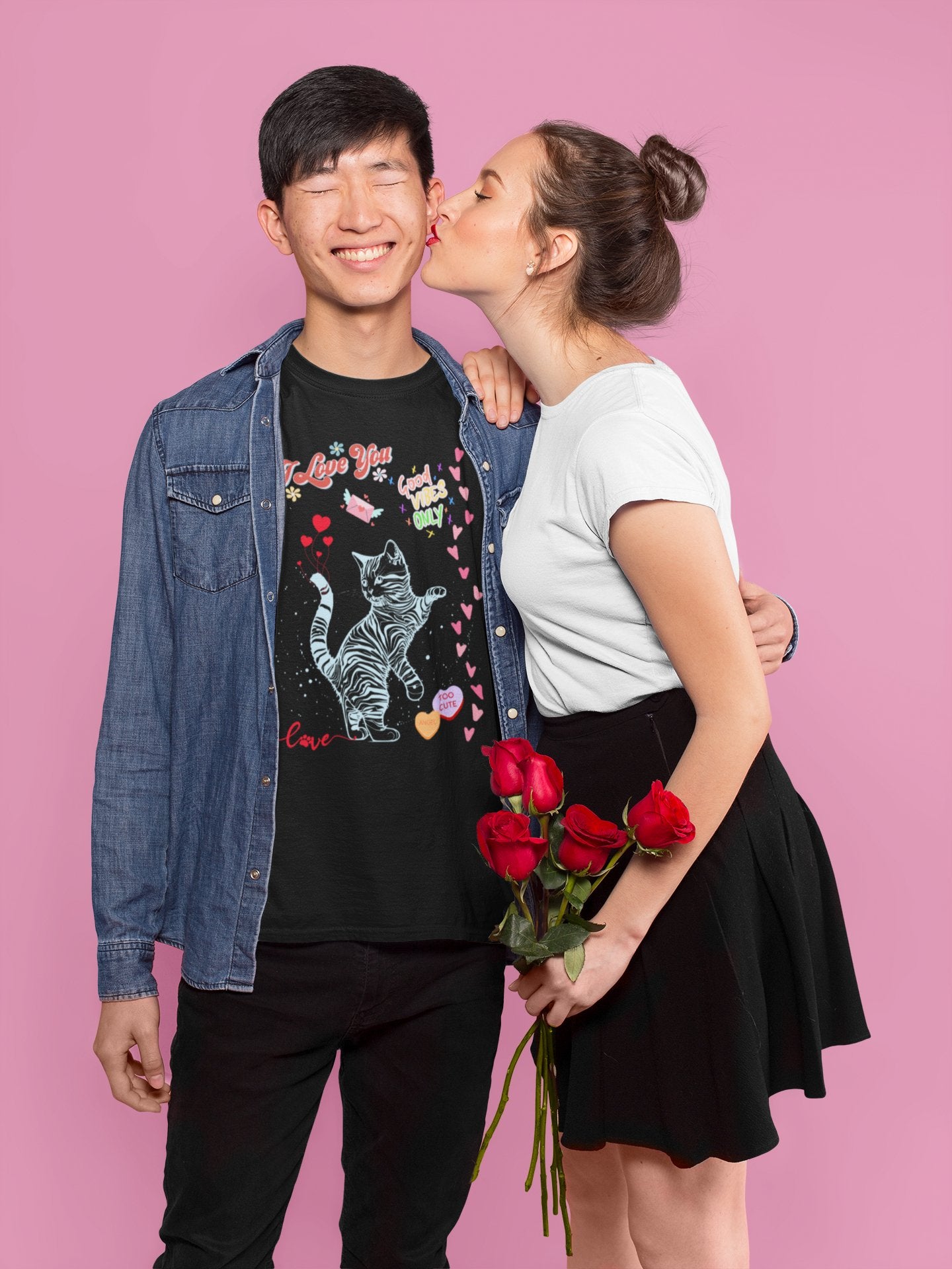 young couple woman kissing his cheek wearing black tshirt i love you good vibes cat hearts on pink background
