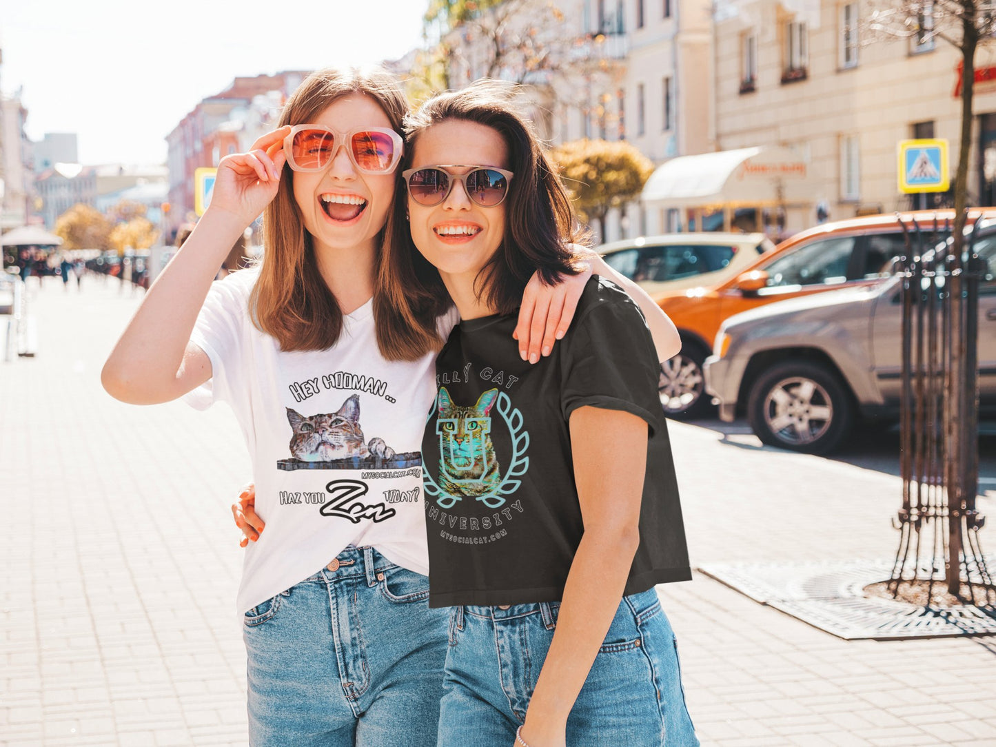 two happy  young sisters walking on the street in the city, wearing a  white with a cat face that says, hey hooman, haz you zen today, t-shirt and a black crop top, featuring a cat face with college emblem over its face that says, silly cat university, mysocialcat.com