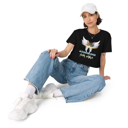 Person wearing a black t-shirt with a graphic design, blue jeans, and white sneakers on a white background