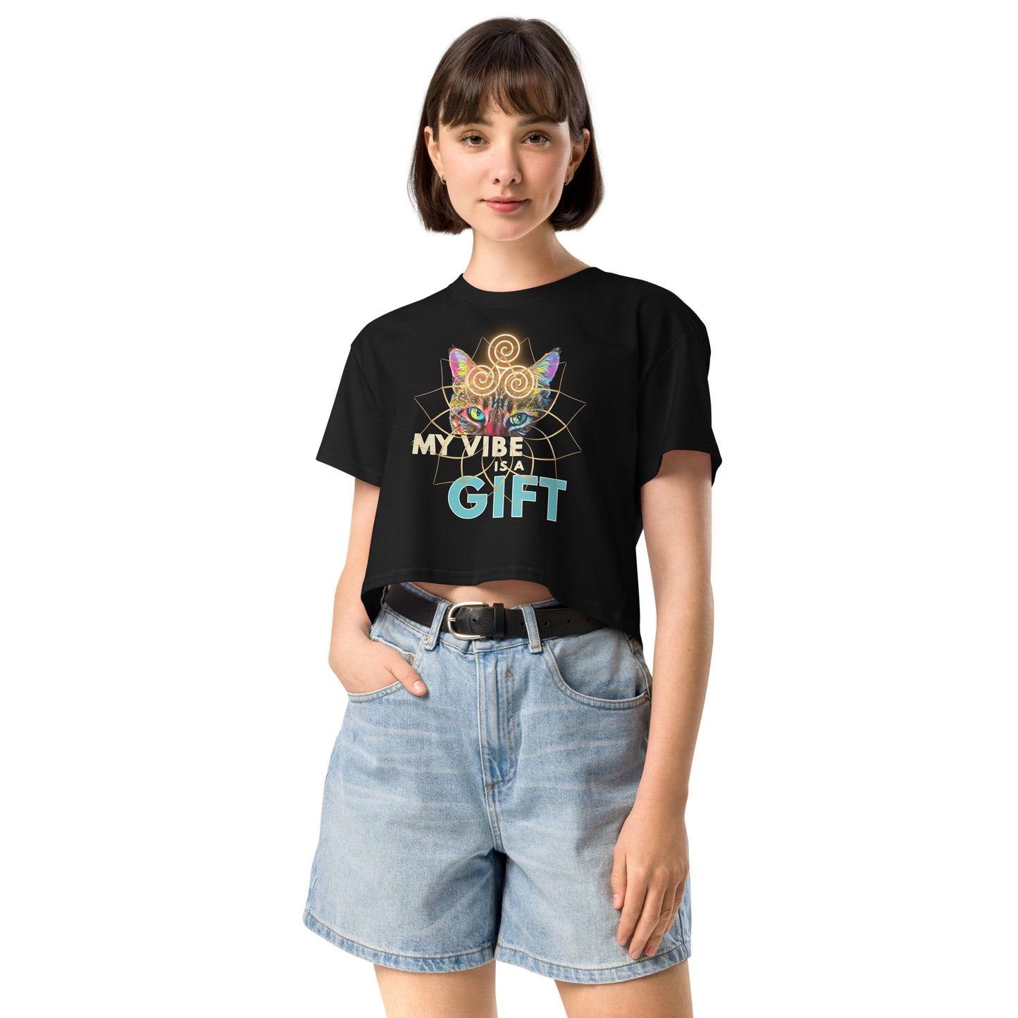 A woman modeling a black short-sleeve graphic T-shirt with a colorful spiderweb and butterfly design and the text 'MY VIBE IS A GIFT', paired with light-wash denim shorts against a plain white background.