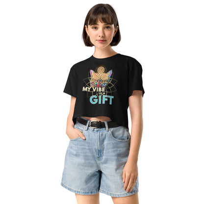 A woman modeling a black short-sleeve graphic T-shirt with a colorful spiderweb and butterfly design and the text 'MY VIBE IS A GIFT', paired with light-wash denim shorts against a plain white background.