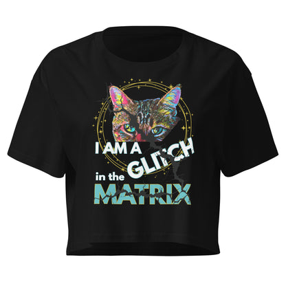A black short-sleeve crop top t-shirt featuring a colorful graphic of a cat's face inside a circular frame with the text 'I AM A GLITCH in the MATRIX' printed on the front.